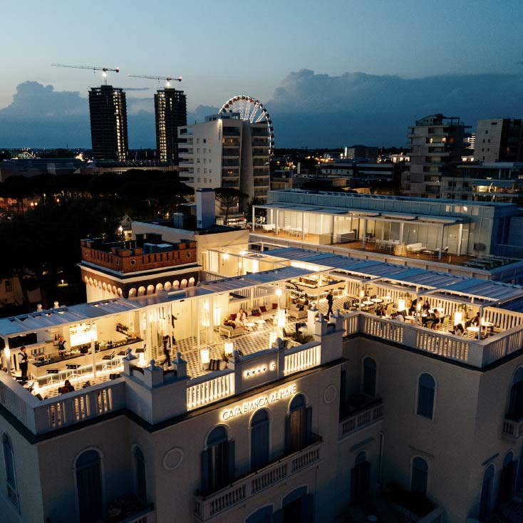 Il rooftop 1923 Casa Bianca illuminato di sera sopra Jesolo